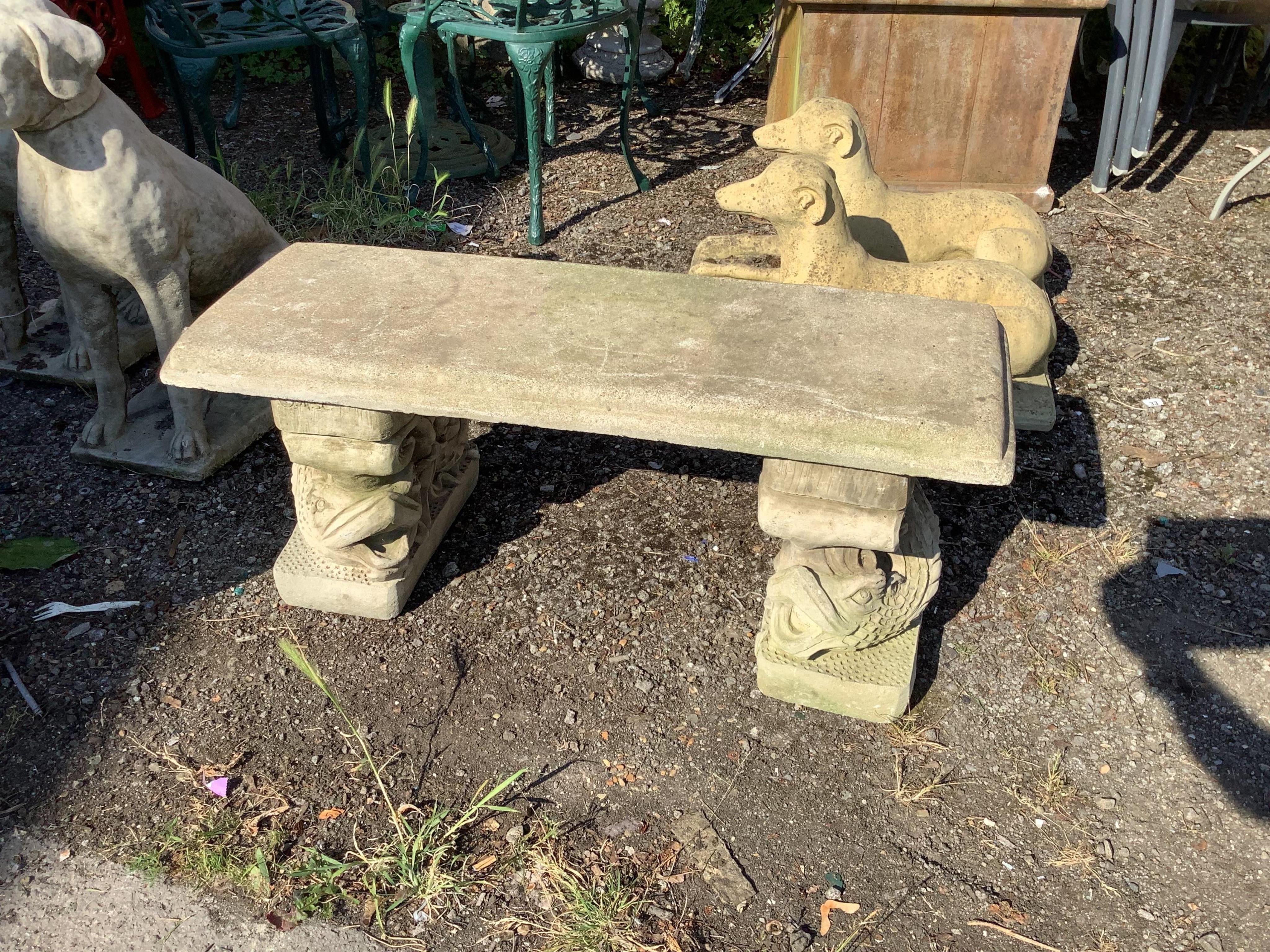 A reconstituted stone garden bench with cast carp supports, width 99cm, depth 36cm, height 40cm. Condition - good
